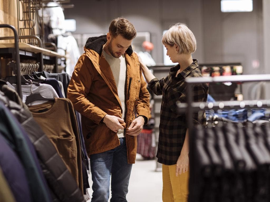 Moški in ženska skupaj pregledujeta oblačila v trgovini, pregledovala različne kose na razstavi